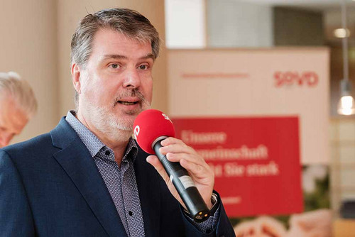 Mann spricht in ein Mikrofon. 