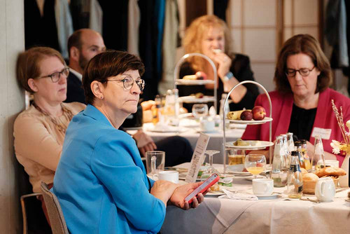 Drei Frauen sitzen an einem Tisch und hören zu. 