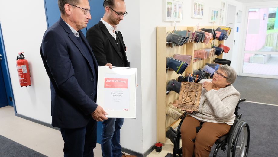 Kirsten Grundmann (rechts) übergibt das SoVD-Gütesiegel an Thomas Haß (links), Bürgermeister von Schwentinental, und den Leiter der DRK-Kita "Pavillon", Sebastian Runde